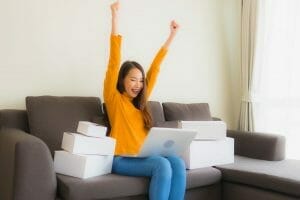 portrait young asian woman using laptop computer for work with parcel box scaled e1614954099972
